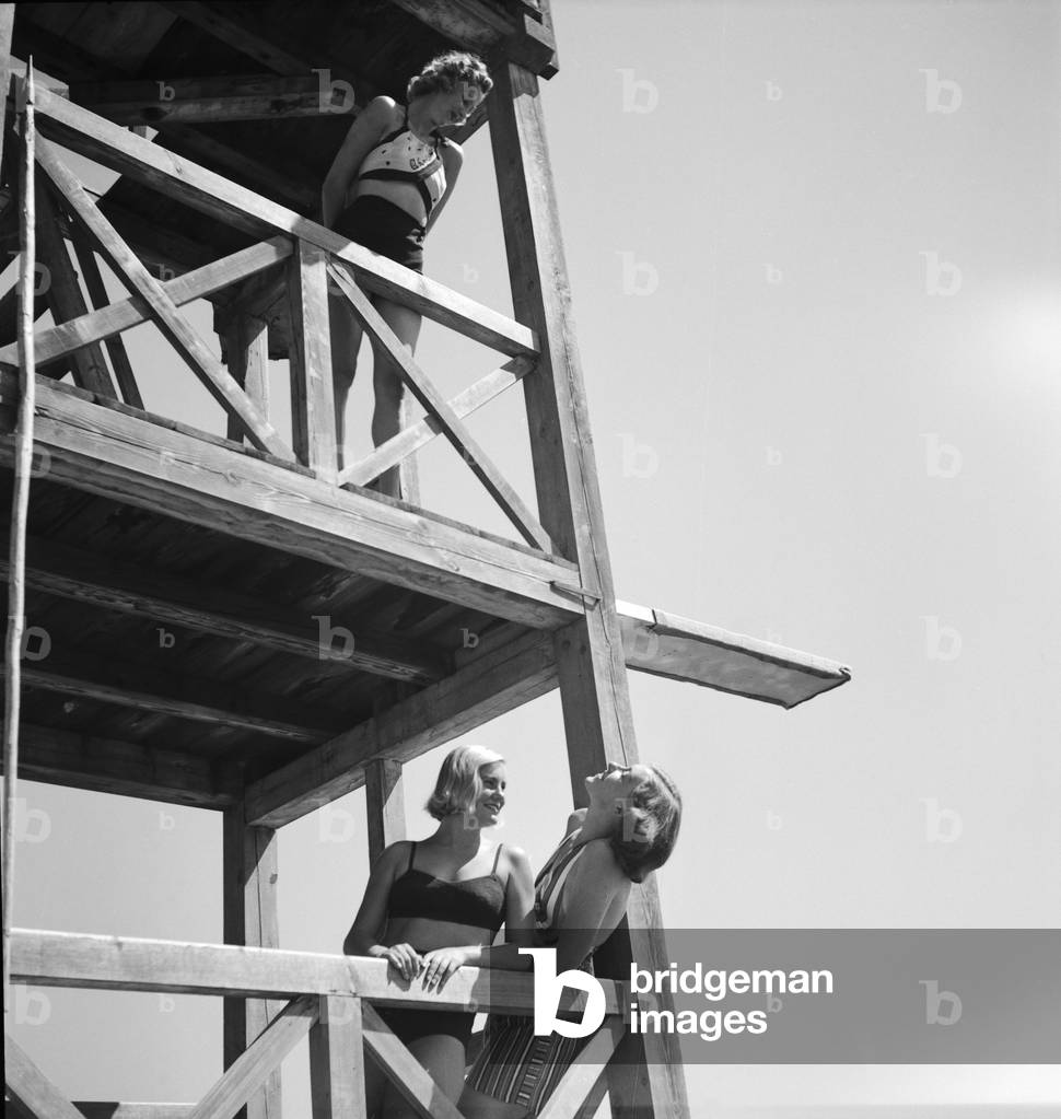 Three young woman on a diving platform on the shore of a lake in the Wachau area in Austria, Germany 1930s (b/w photo)