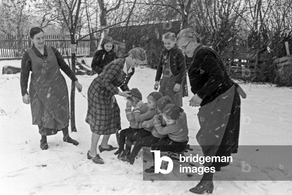 Riding a sleigh at christmas at a family with quadruplet girls, Germany 1930s (b/w photo)