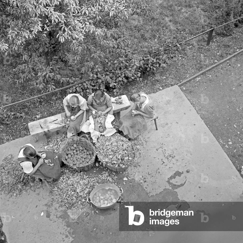 Peeling potatoes in the shadow of Stahleck castle at Bacharach, Germany 1930s (b/w photo)