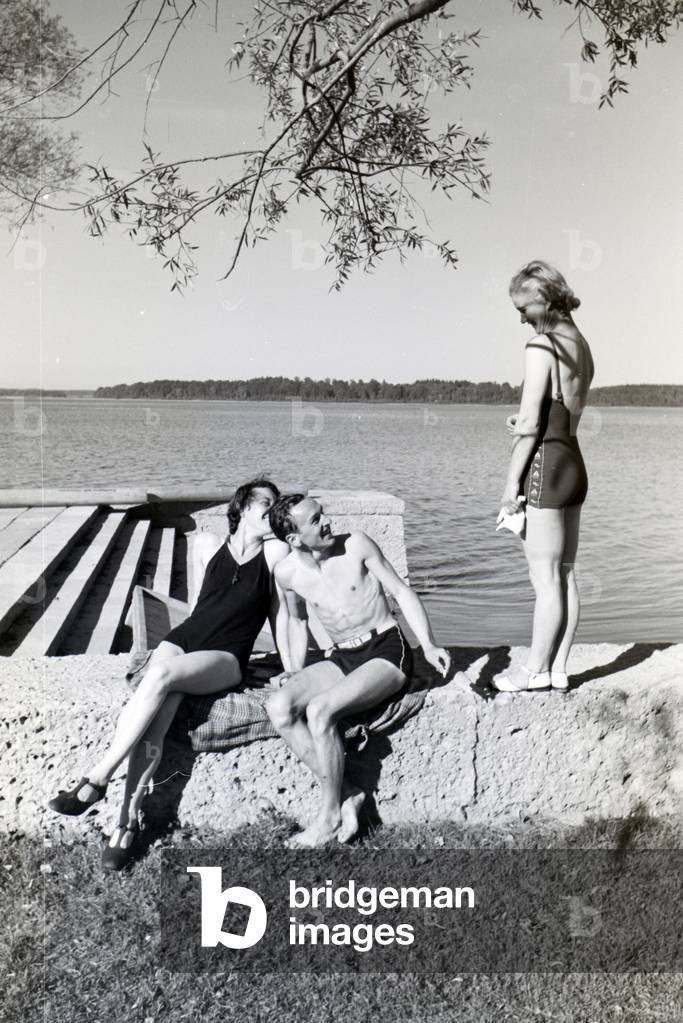 Two young women and a young man sunbathing and swimming in the Chiemsee, Dermany 1930s (b/w photo)