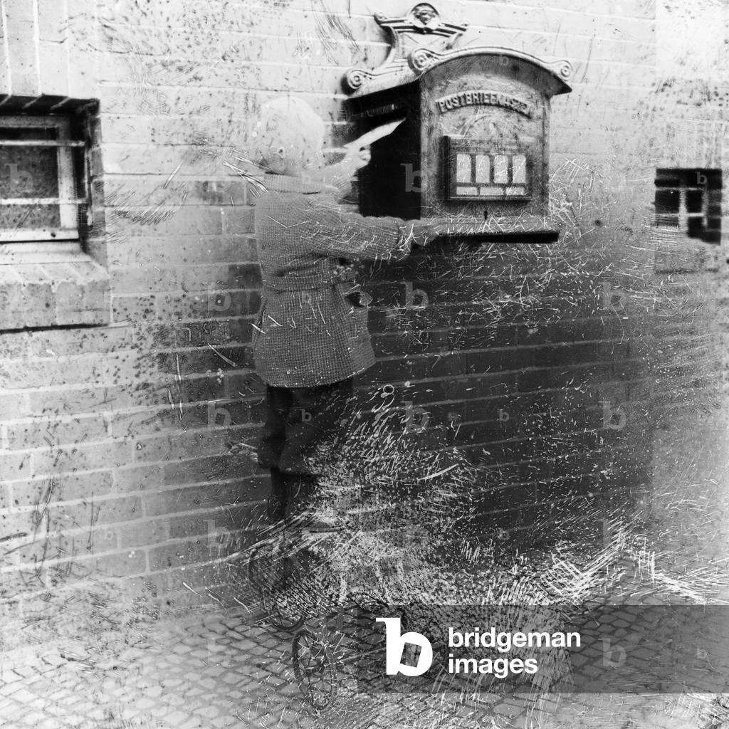 A little boy bringing a letter to the letter box, Germany 1920s (b/w photo)