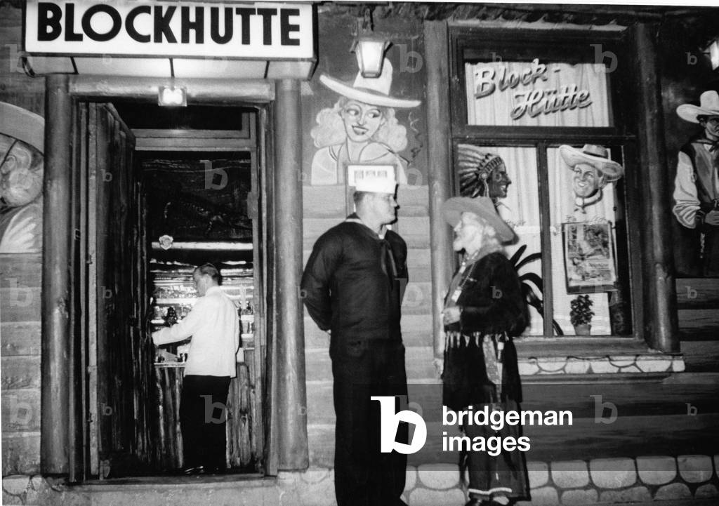A sailor and a carney of the nightclub Blockhuette are talking in front of the club's entrance at Hamburg Reeperbahn, 1950s