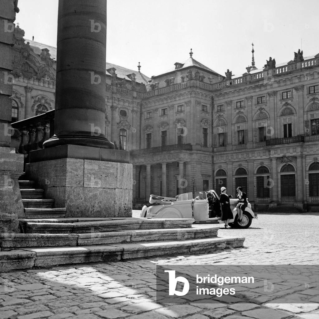 Two women with a convertible at the courtyard of Wuerzburg Residence, Germany 1930s (b/w photo)