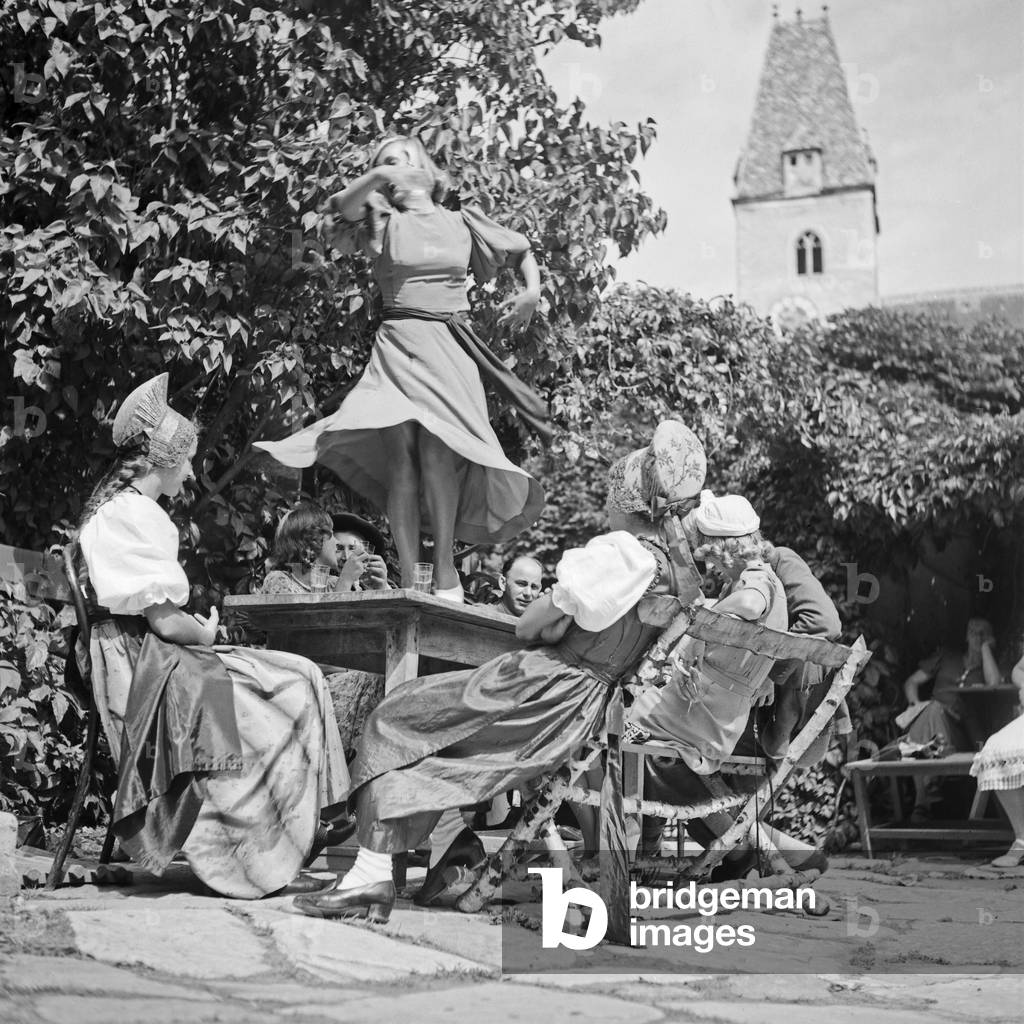 A young woman tasting the wine of the Wachau area in Austria and dancing on the table, Germany 1930s (b/w photo)
