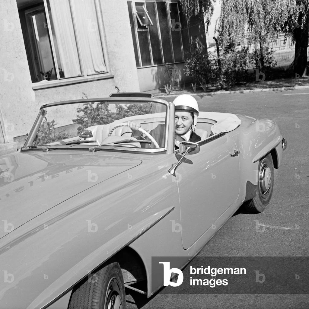 Irish singer Johnny Dane wearing a helmet in his Mercedes Benz 190 SL convertible at Hamburg, Germany 1950s