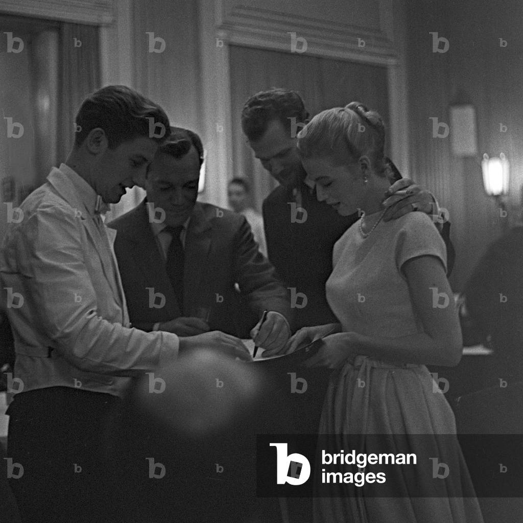 American actor and chansonnier Eddie Constantine and Danish singer duo Nina and Frederik sigining autographs for the waiters of a restaurant at Hamburg, Germany 1950s