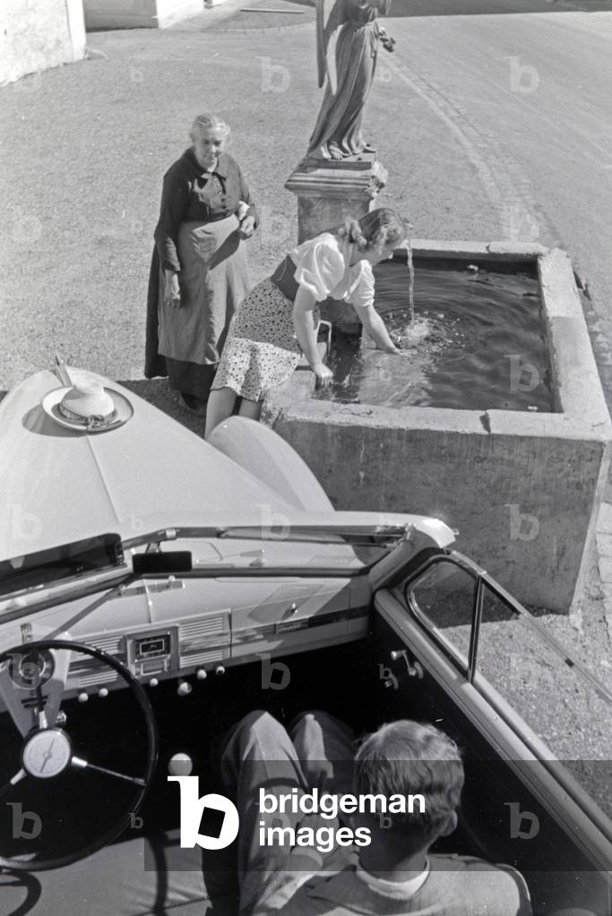 Austrian actress Gusti Wolf refreshing at a well on holiday at the countryside, Germany 1930s (b/w photo)