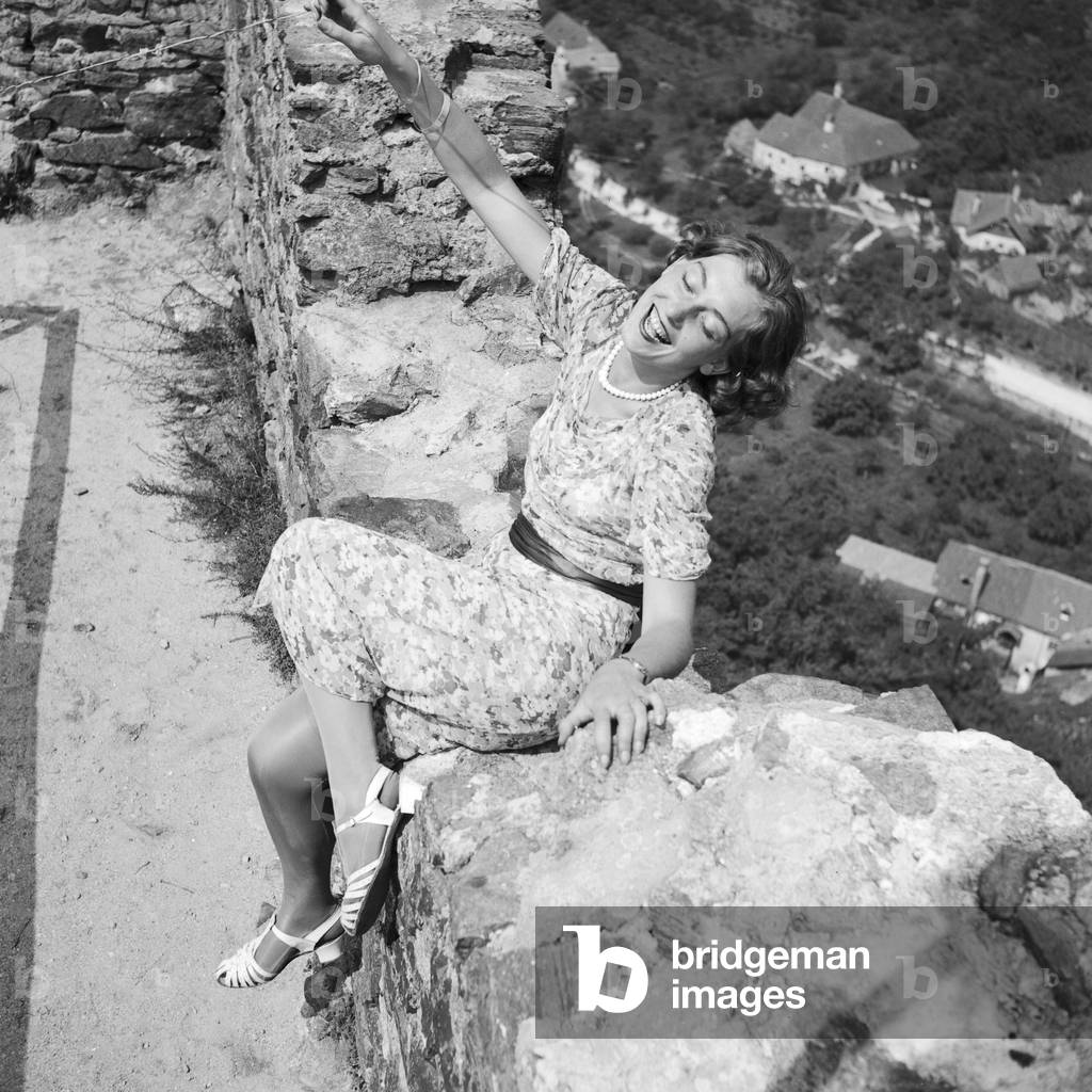 A young woman sitting in the remains of an old castle in the Wachau area in Austria, Germany 1930s (b/w photo)
