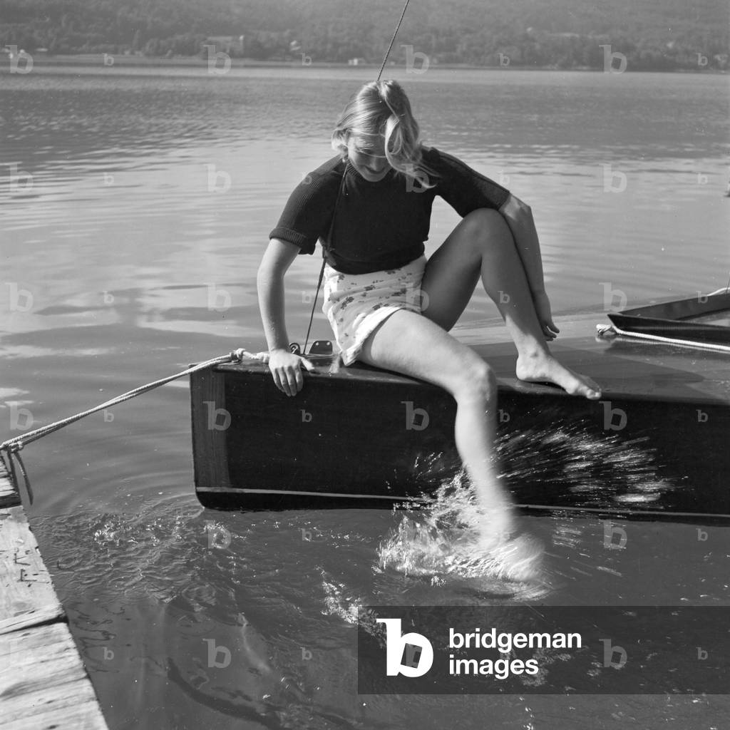 A young woman on a boardwalk on the shore of a lake in the Wachau area, Germany 1930s (b/w photo)
