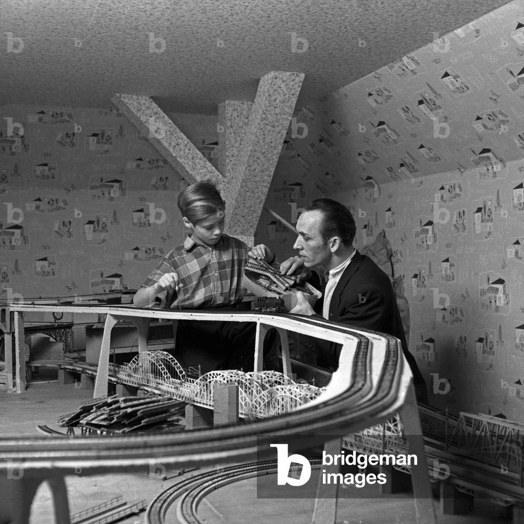 A father constructing a model train complex at Hamburg with his son, Germany 1950s
