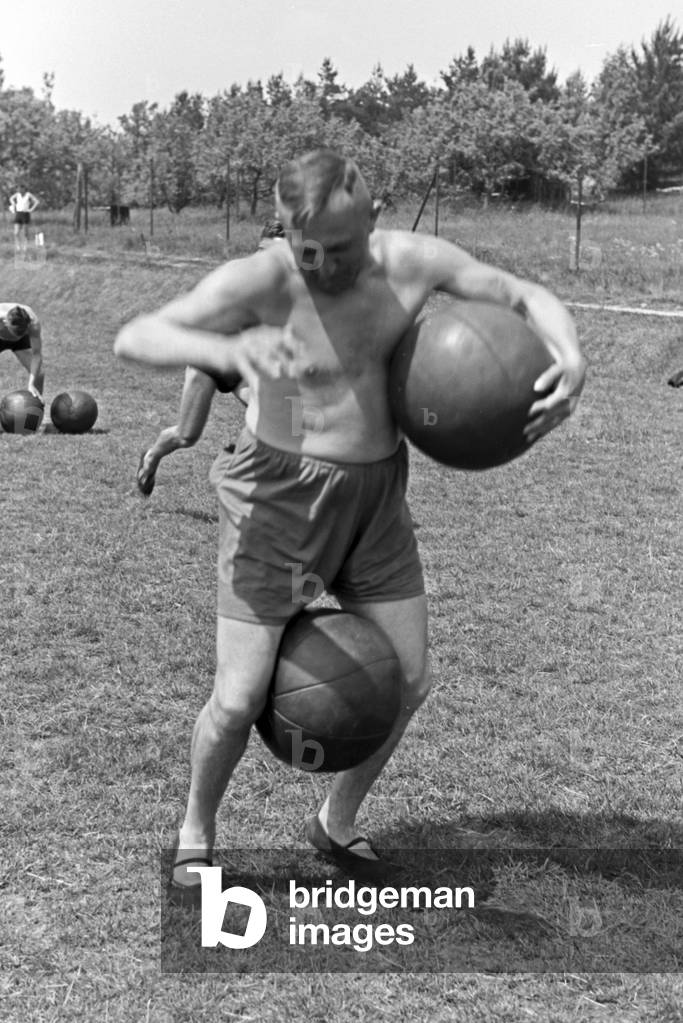Running exercise with medicine balls at the sports ground of the sports club house at Belzig in Brandenburg, Germany 1930s (b/w photo)