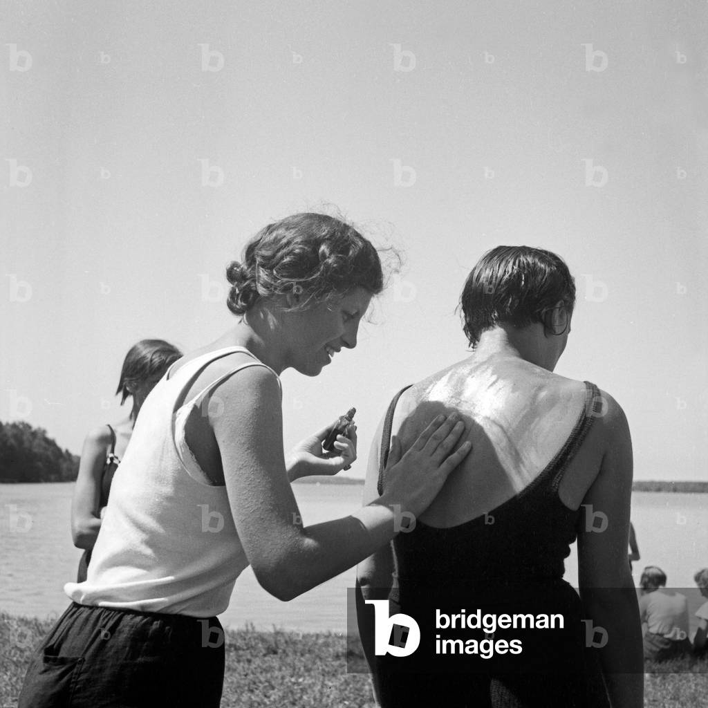 Applying suntan lotion is the best rescue against sunburn at the leisure camp of the Deutsche Arbeitsfront at Altenhof, Brandenburg, 1930s (b/w photo)