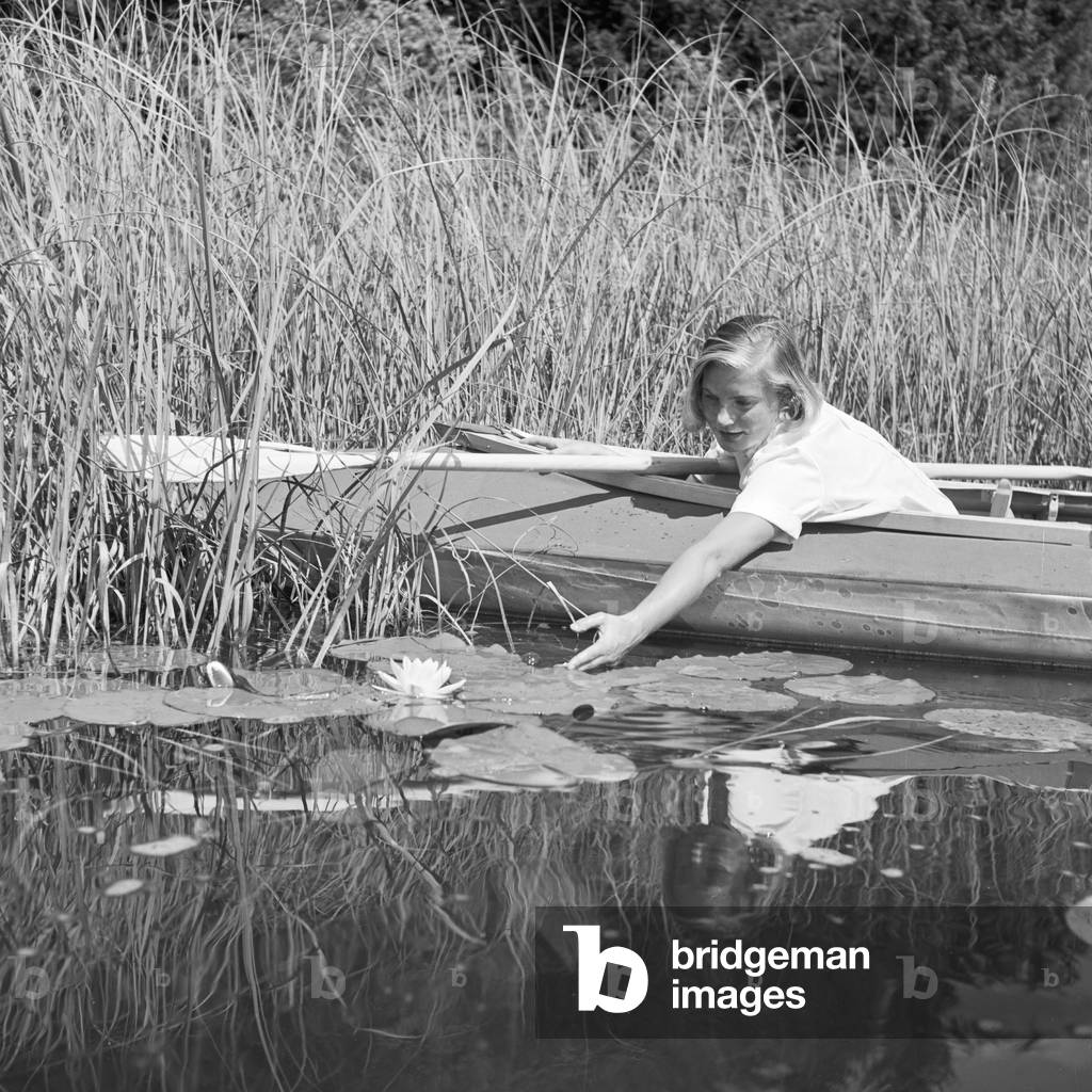 A young woman with her folding boat in the reed of a lake in the Wachau area, Germany 1930s (b/w photo)