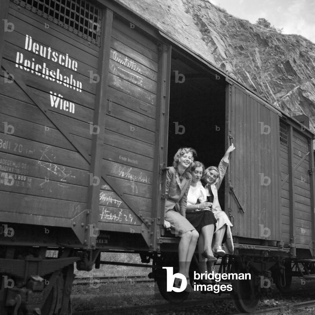 Three young woman in a freight waggon of a train to Amstetten in Austria, Germany 1930s (b/w photo)