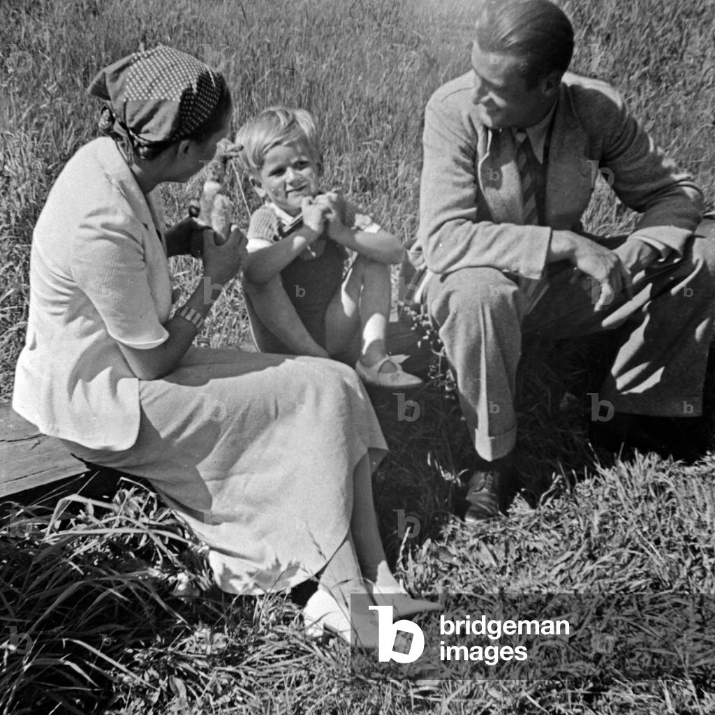 A family sitting on a lawn at their Sunday trip, Germany 1930s (b/w photo)