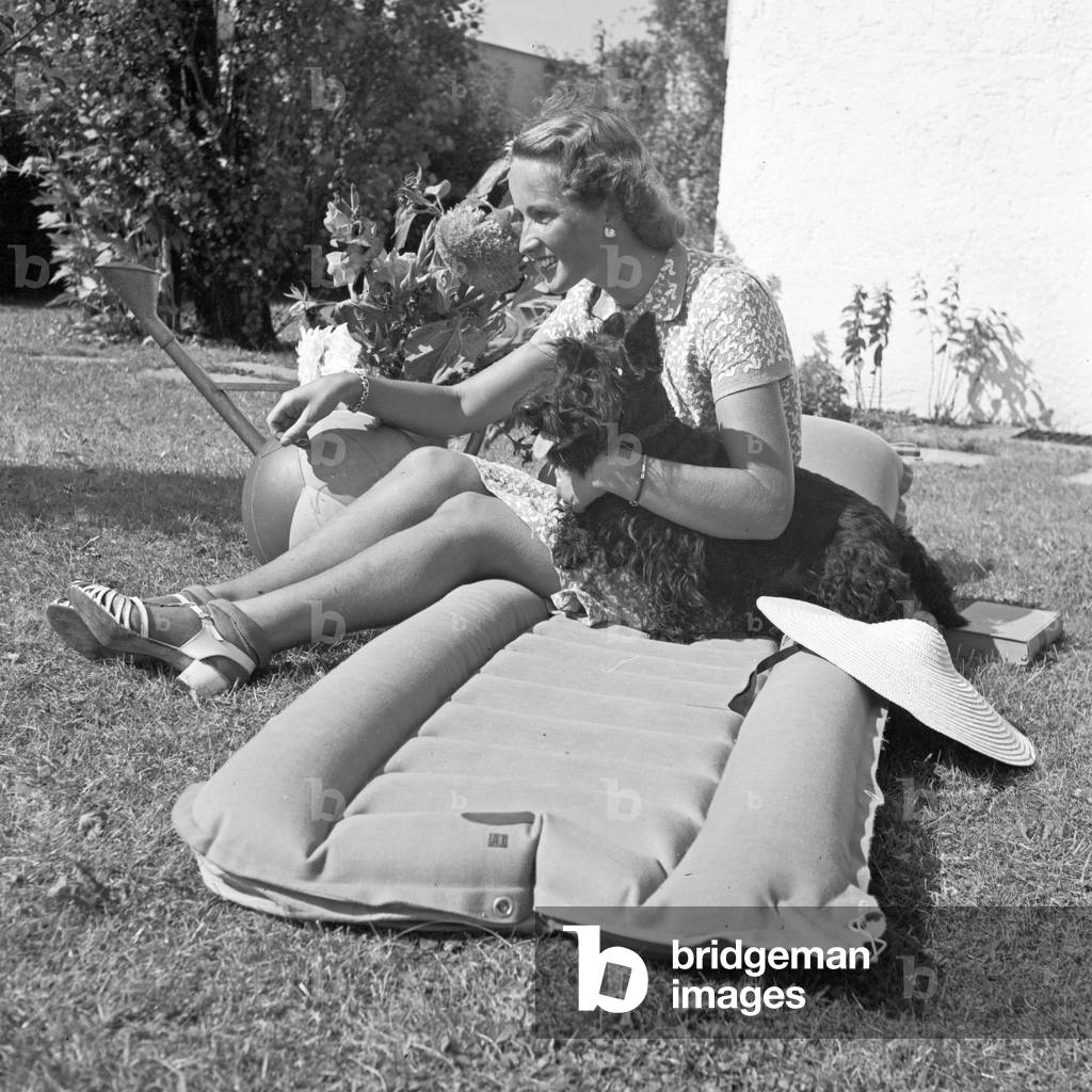 A young woman with her dog on a lawn, Germany 1930s (b/w photo)
