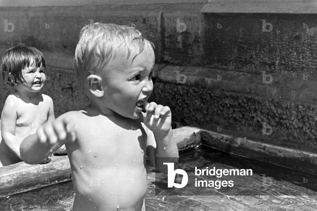 Playing toddlers in the open-air swimming pool on a hot summer day, Germany 1930s (b/w photo)