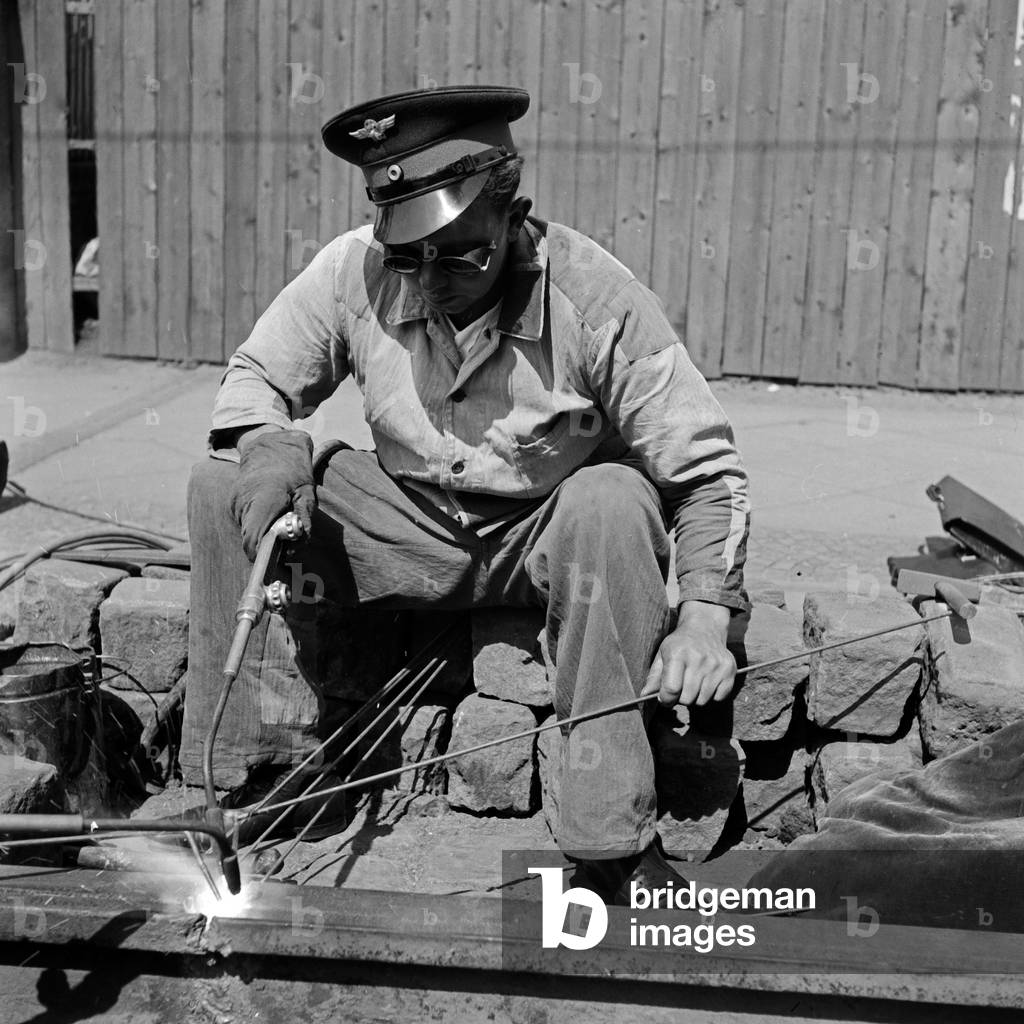 A staff member of Deutsche Reichsbahn railway company doin some welding at railroad track at Wuppertal, Germany 1930s (b/w photo)