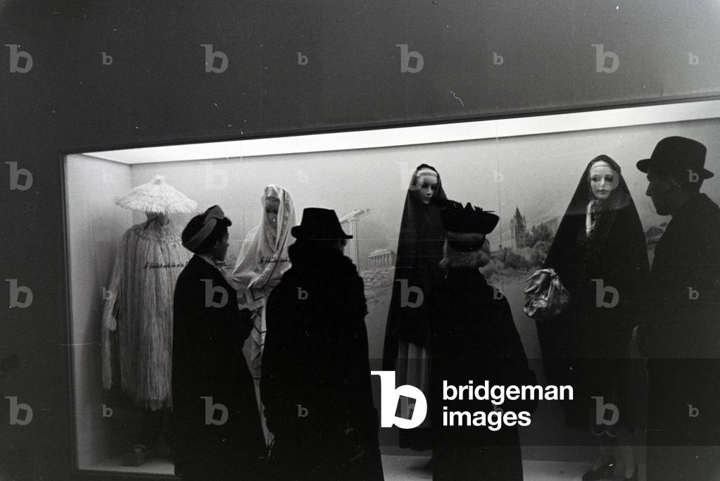 Visitors to a fair in front of a display case with traditional costumes, on the occasion of the Wiener Modewoche in the house of fashion 