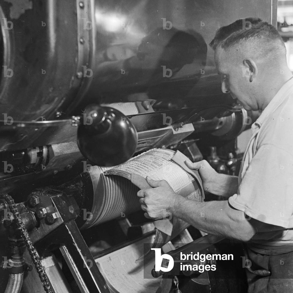 A man inserting a first print into a printing machine, Germany 1930s (b/w photo)