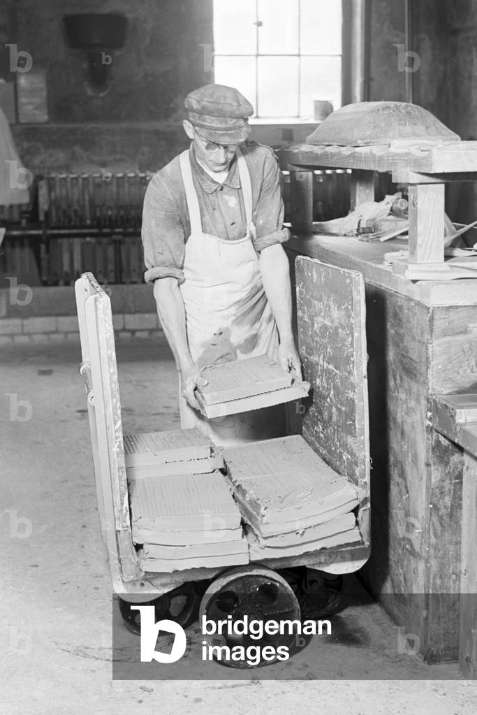 A ceramists of the State Porcelain Manufactory Berlin sorts raw ceramic plates for the bisque firing, Germany 1930s (b/w photo)