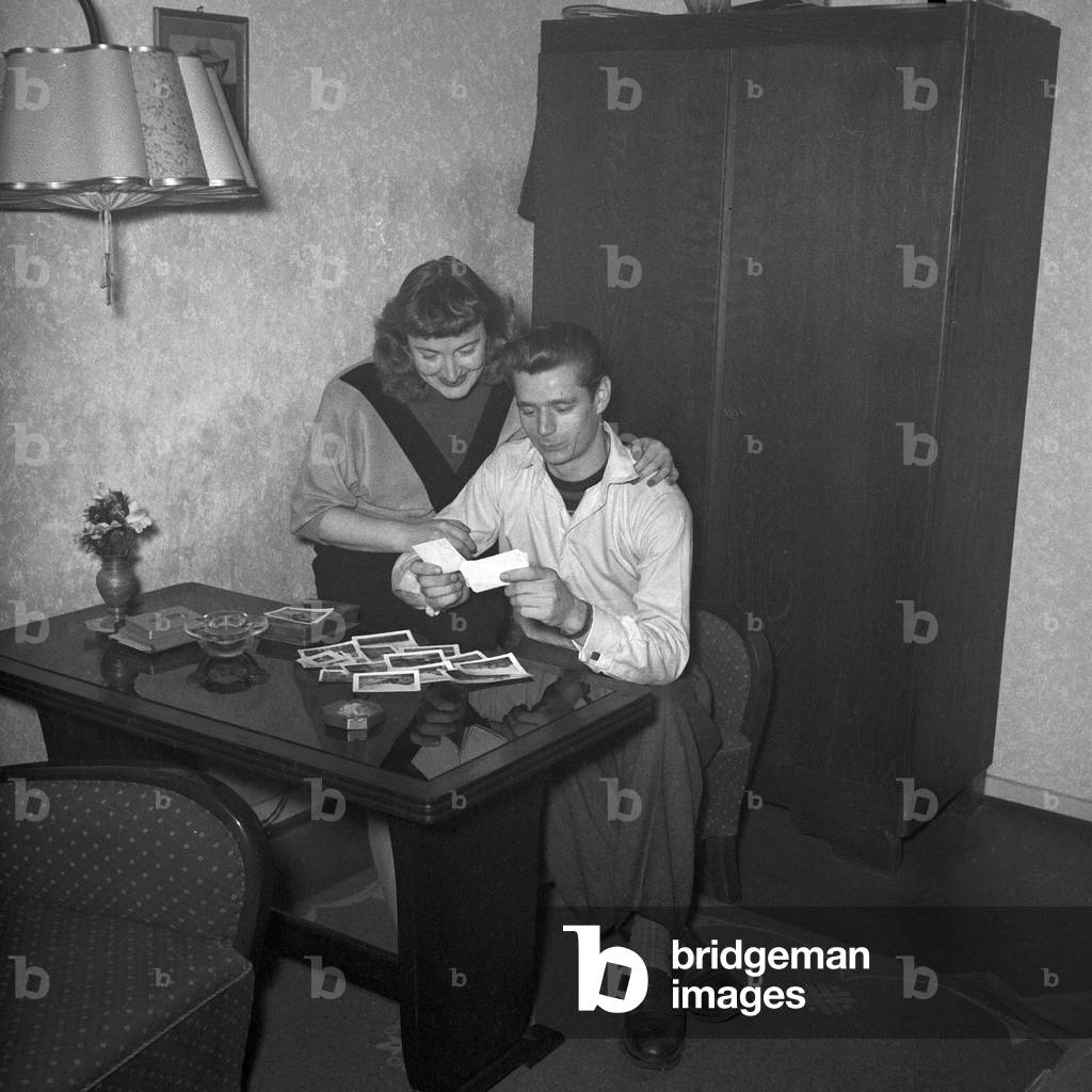 A man and a woman watching photos in their living room, Germany 1954