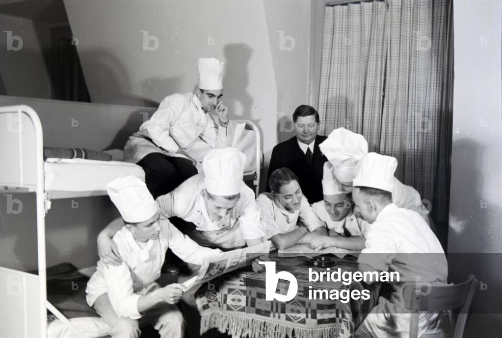 The trainees of the Reichskochschule are passing the time with the paper in the sleeping rooms during a seminar break, Frankfurt am Main, Germany 1930s (b/w photo)