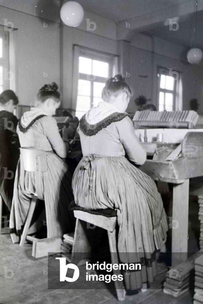 Female cigar rollers wearing a Marburg garb, costume at work in a cigar fabric near Marburg, Germany 1930s (b/w photo)