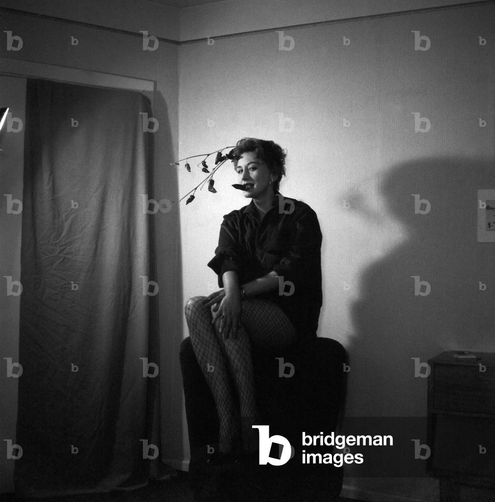 German singer, actress and dancer Evelyn Kuenneke at a photo shooting, sitting on the backrest of a cocktail chair, a leaf in her mouth, Hamburg 1956