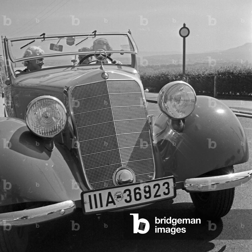 Two women and a man on their way in a Mercedes Benz convertible, Germany 1930s (b/w photo)