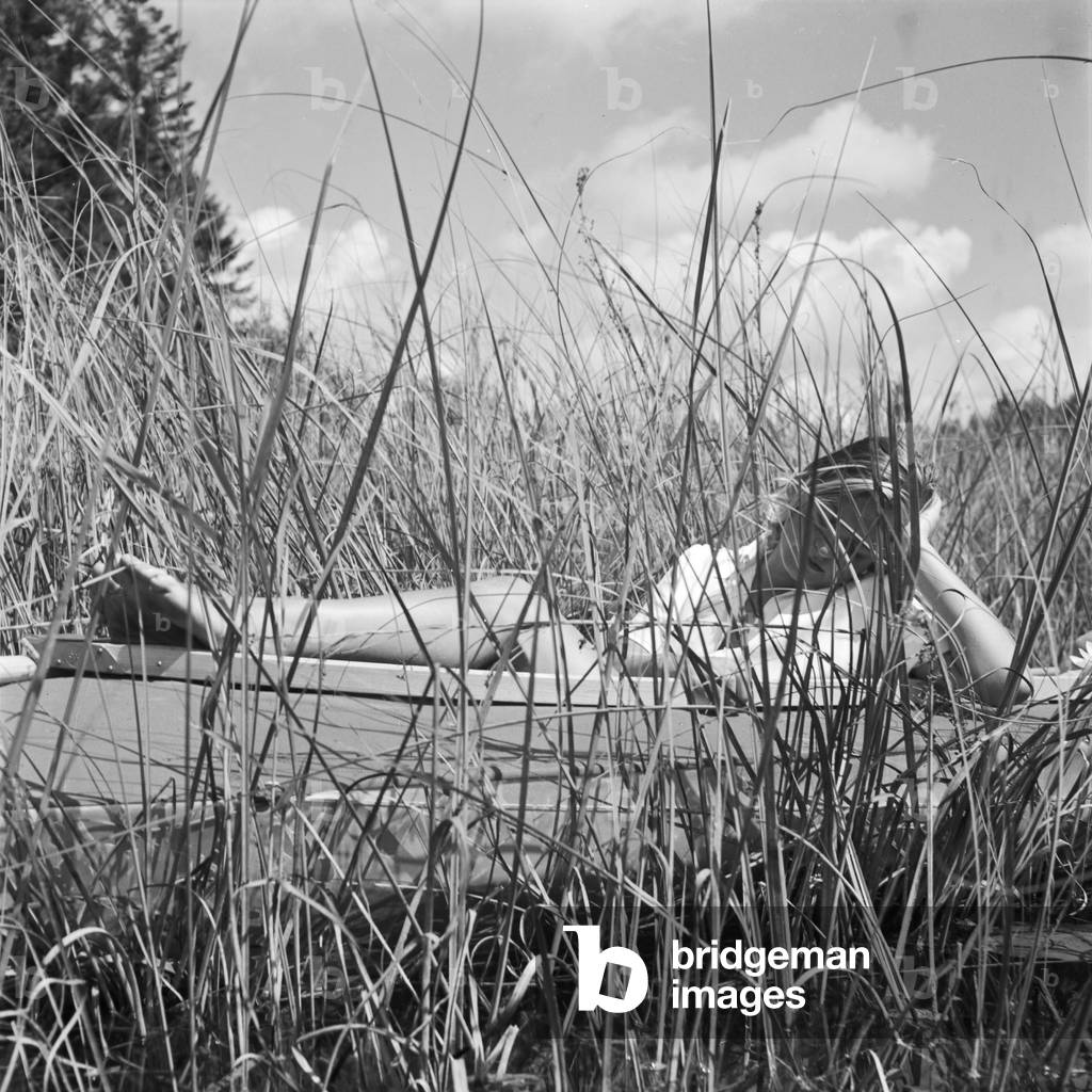 A young woman with her folding boat in the reed of a lake in the Wachau area, Germany 1930s (b/w photo)