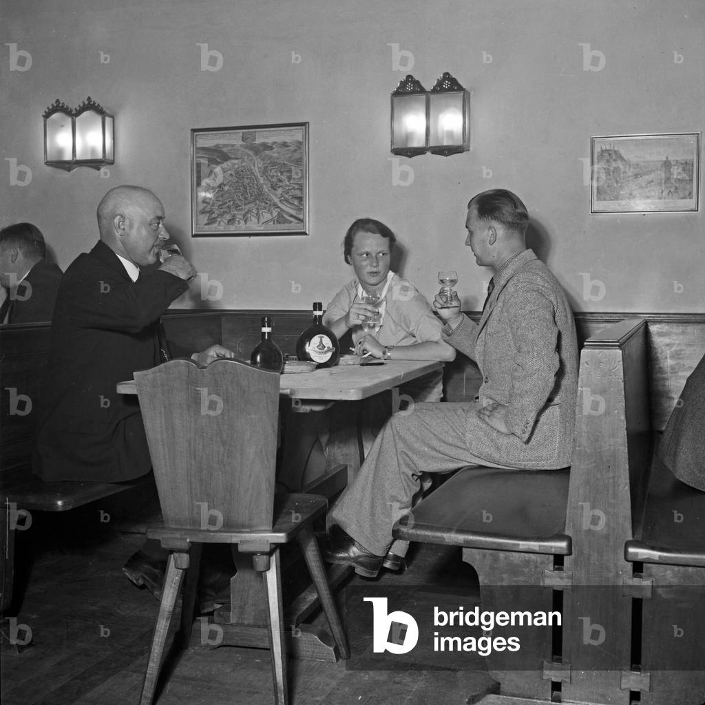 At the Juliusspital vineyard guests enjoying Franconian wine from Bocksbeutel bottles, Germany 1930s (b/w photo)