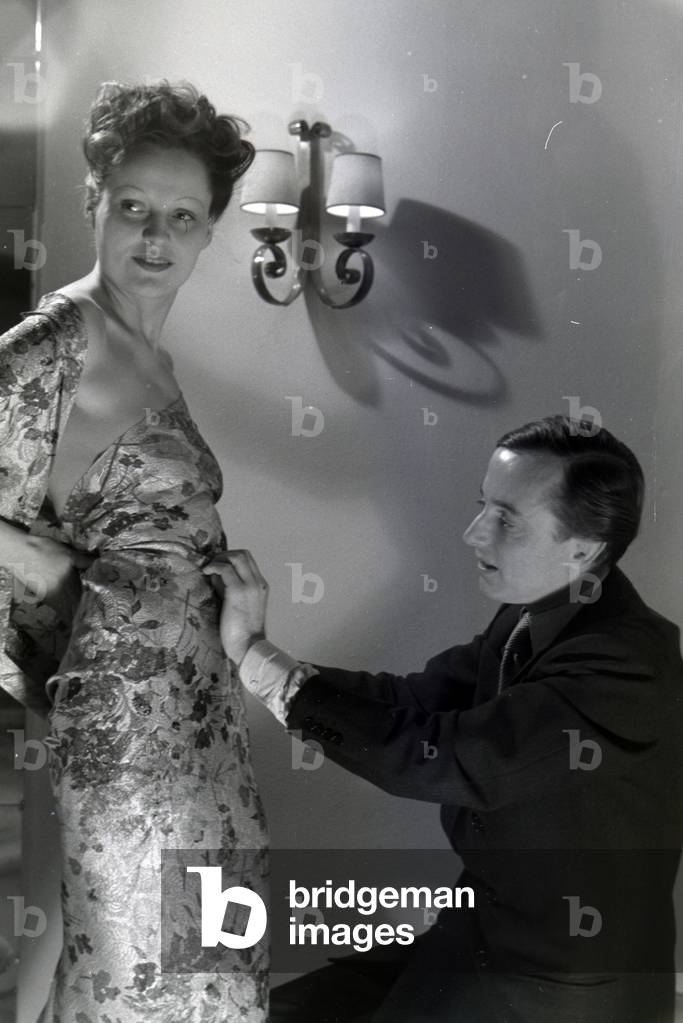 The fashion designer Heinz Schulze-Bibernell and a model trying a dress, Germany ca.1939 (b/w photo)