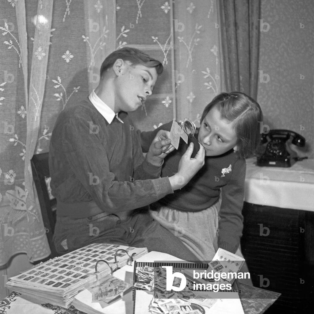 A boy showing a little girl his hobby: his stamp colletion, Germany 1950s