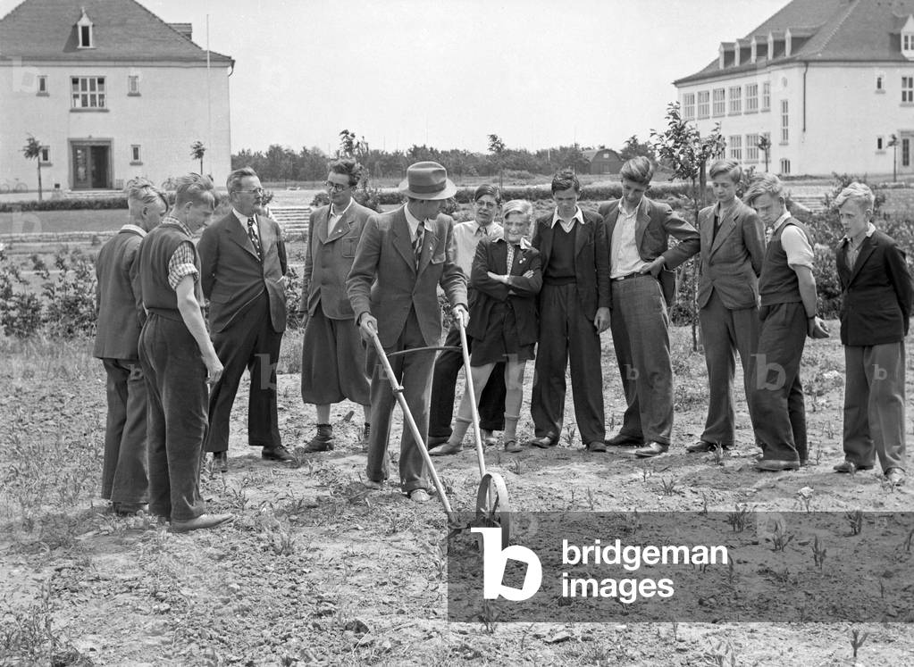 Apprentice learn how to work with agricultural equipment at the exercising field of their vocational school, Germany 1930s (b/w photo)