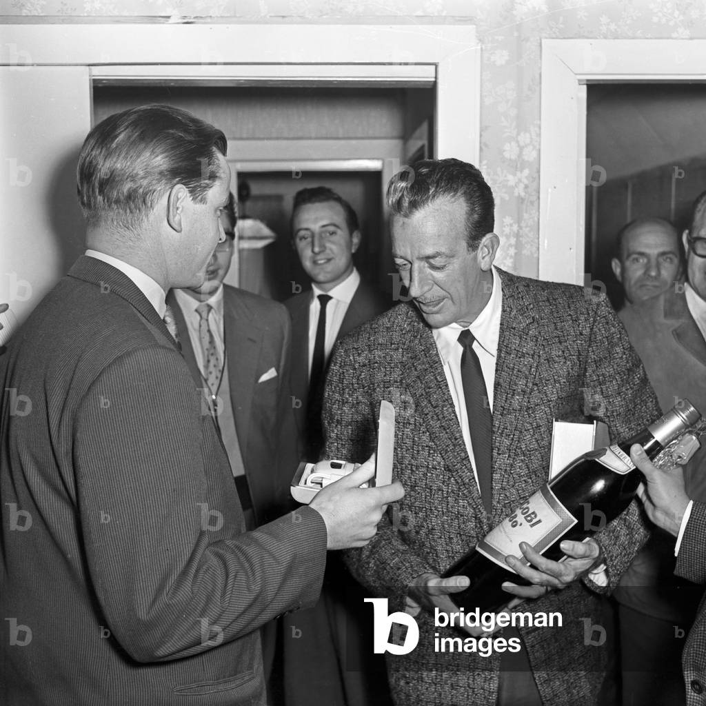 Dutch German show presenter and entertainer Lou van Burg getting a magnum bottle of brandy as a present at Hamburg, Germany 1950s