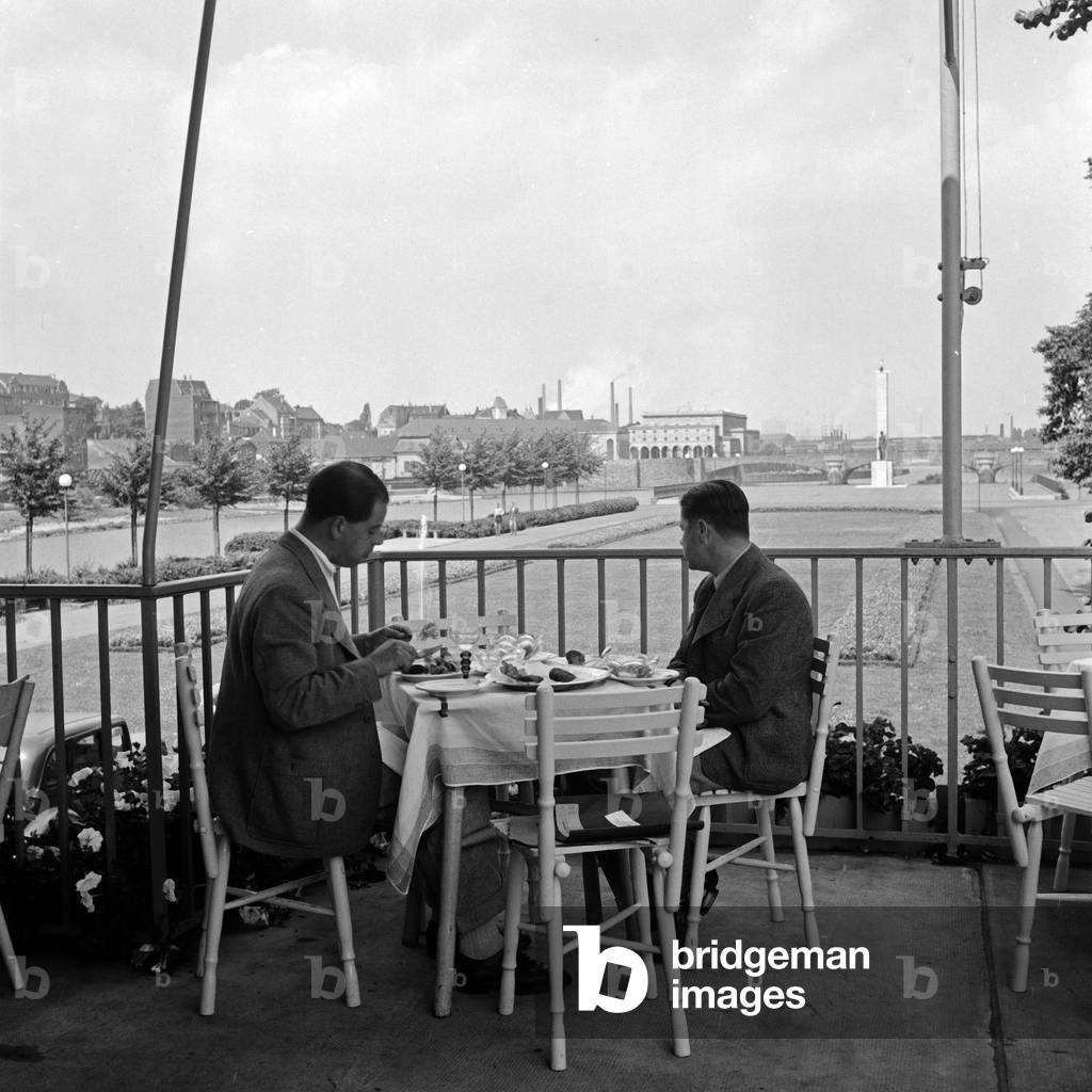 Two men having outdoor catering at a terrace of a restaurant at Muelheim, Germany 1930s (b/w photo)