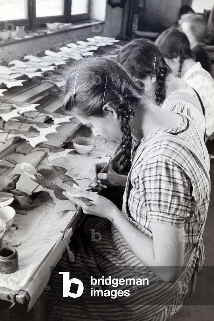 Employees of the Heller Kunst workshops in the Eifel painting sawn out wooden figures, Germany 1930s (b/w photo)