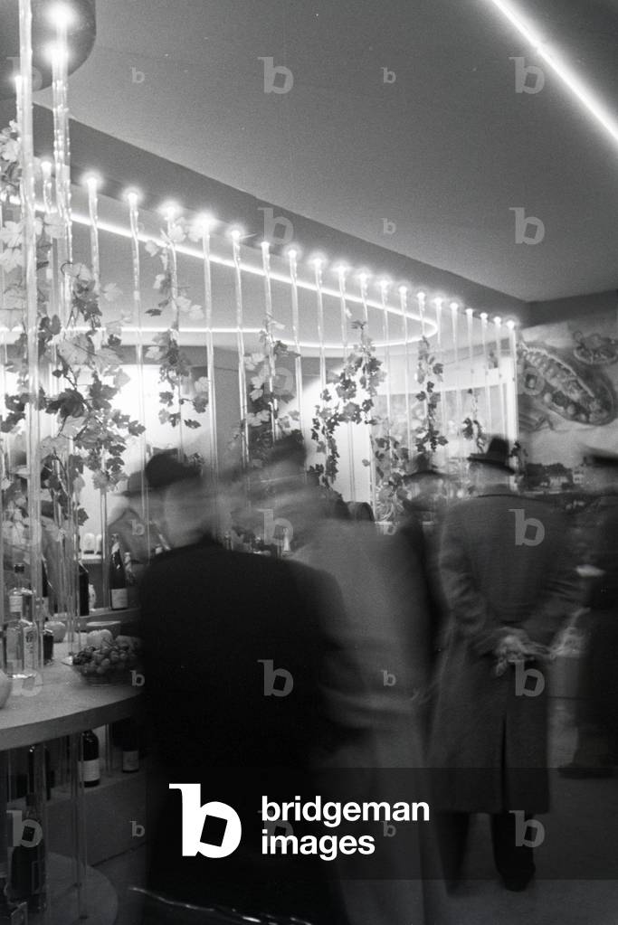 Visitors of the Leipziger Frühjahrsmesse at a stand with traditional spirits, Germany 1941 (b/w photo)