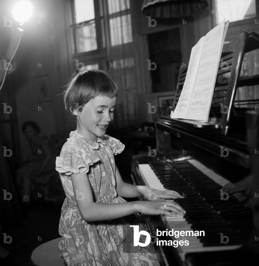 A little girl playing a grand piano