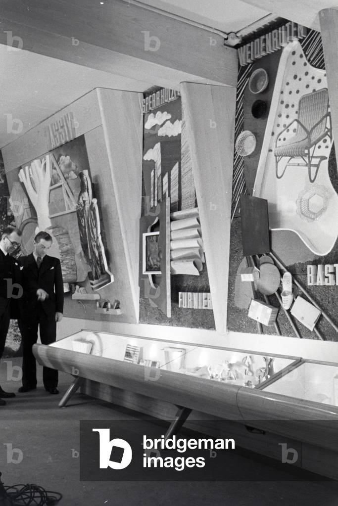 Employees of the Leipziger Frühjahrsmesse in front of a wall with the building material wood and a display cabinet, Germany 1941 (b/w photo)