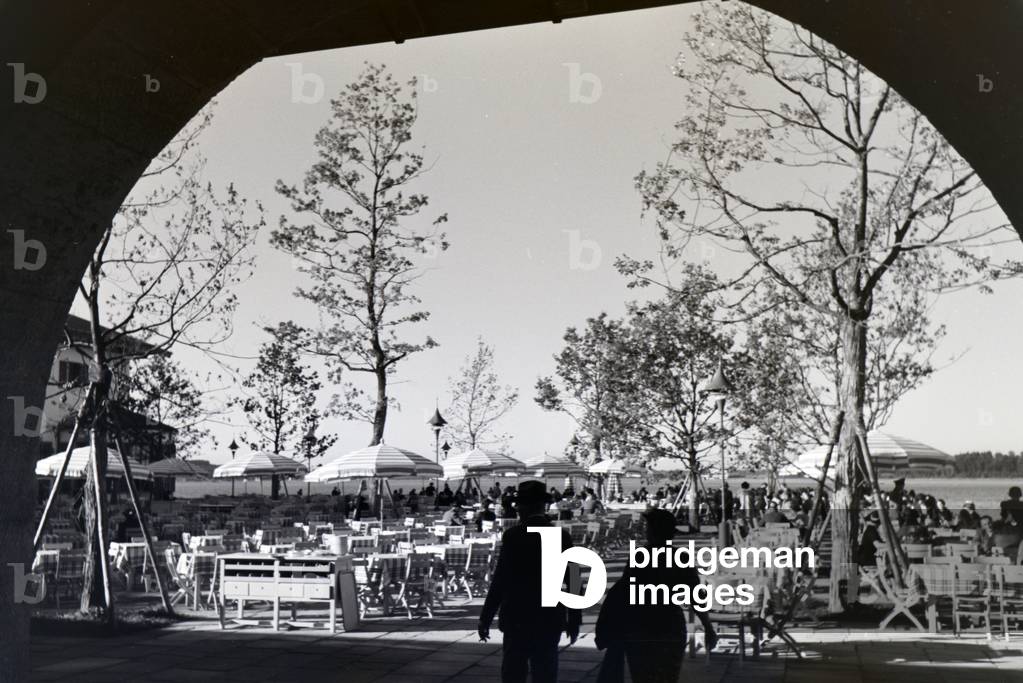 View of the well-frequented sun terrace of a café at the Chiemsee, Germany 1930s (b/w photo)