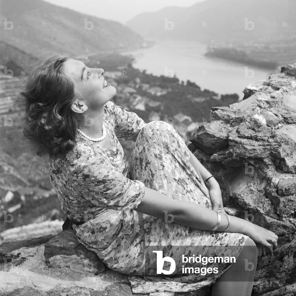 A young woman sitting in the remains of an old castle in the Wachau area in Austria, Germany 1930s (b/w photo)