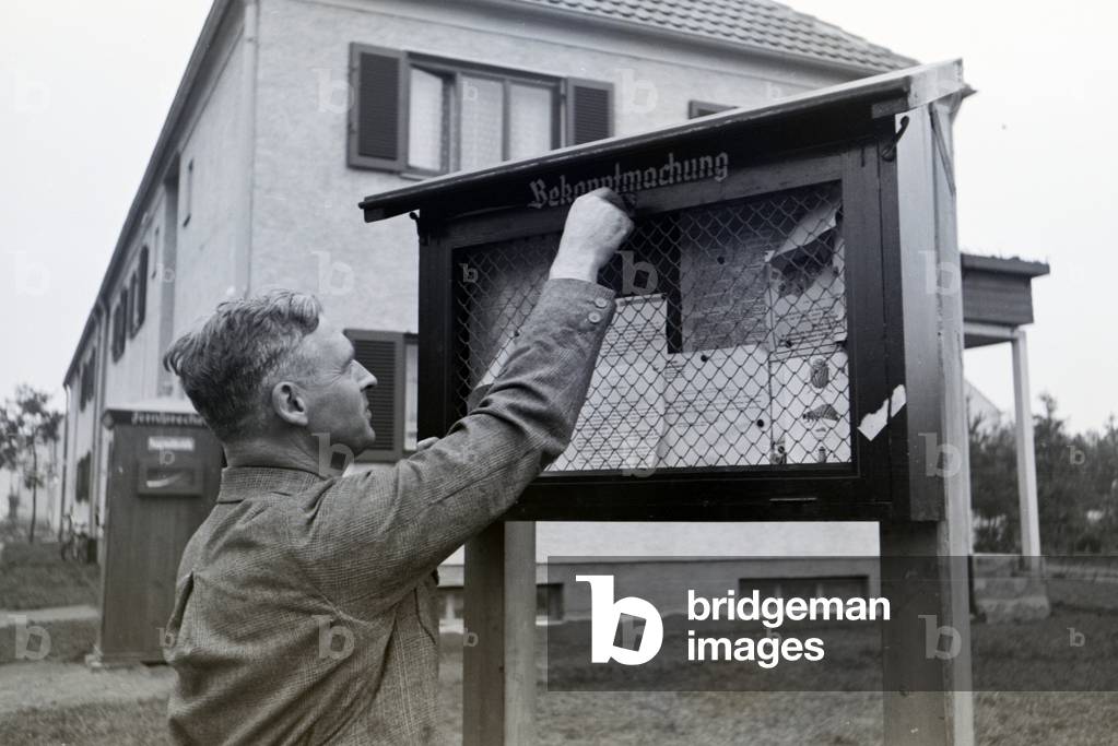 The mayor of Zeppelinheim and airship captain Hans von Schillerunlocking the public noticeboard of the community, near Frankfurt am Main, Germany 1930er (b/w photo)