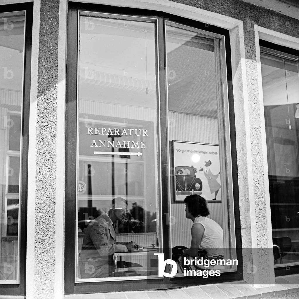 A woman sitting in the service department of a Volkswagen car dealeship at Hamburg, Germany 1950s