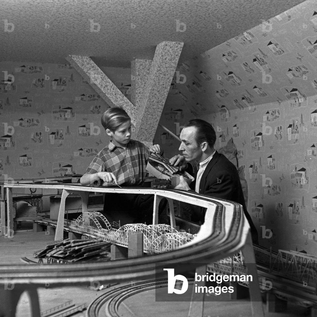 A father constructing a model train complex at Hamburg with his son, Germany 1950s
