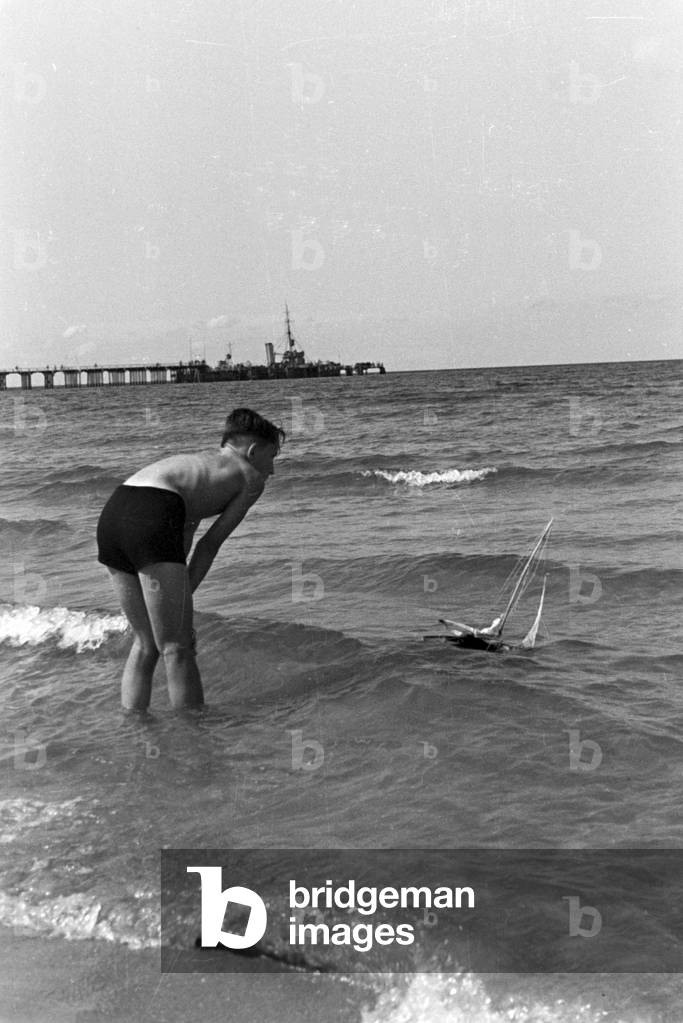 A boy with his toy boat at the Baltic Sea, Germany 1930s (b/w photo)