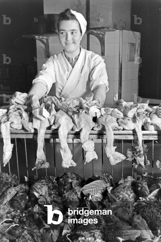 A woman with fresh poultry at the kitchen of a restaurant, Germany 1930s (b/w photo)