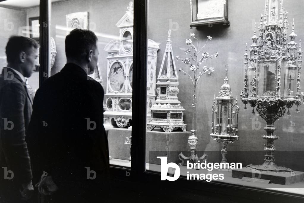 Visiors looking at a vitrine with exhibitions pieces in the Treasury of Munich Residenz, Germany 1930s (b/w photo)