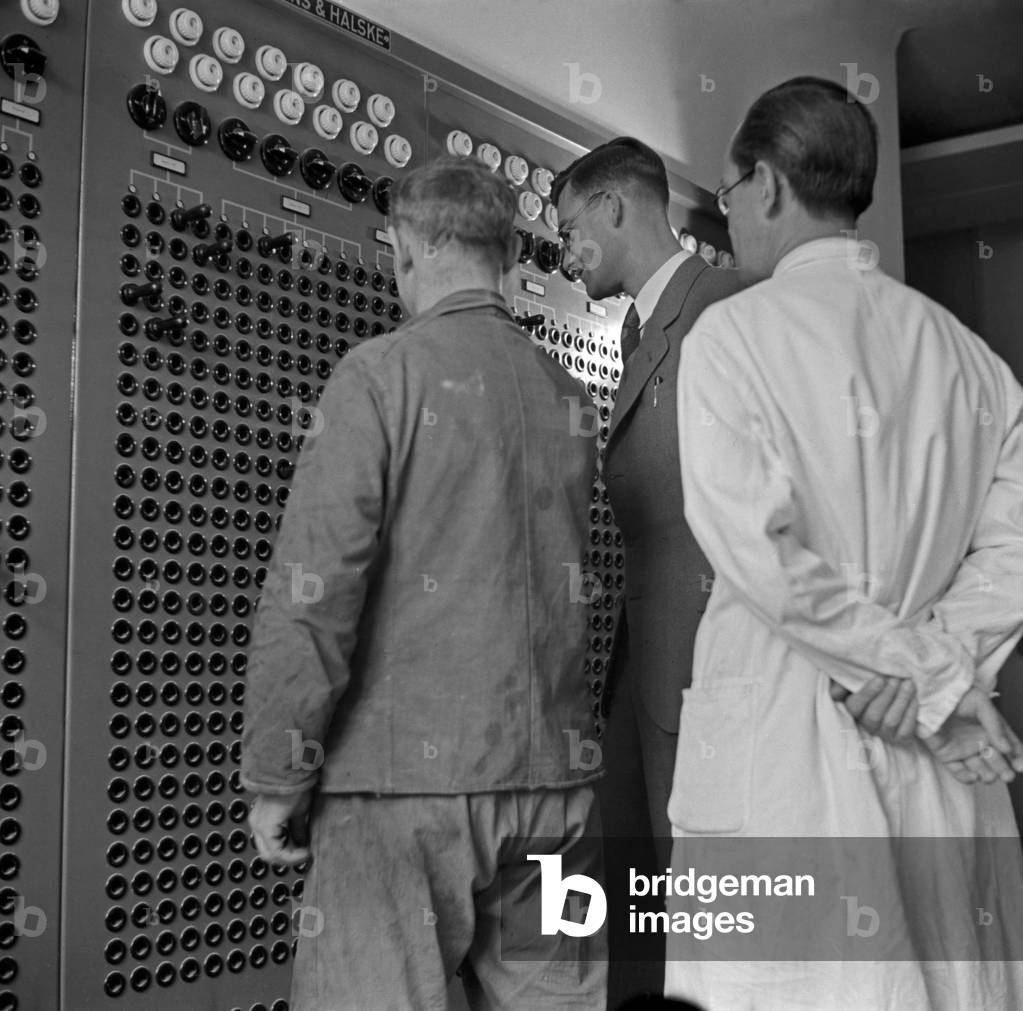 Scientists and a worker at an electronical control unit at the Kaiser Wilhelm Institute for physics in Berlin Dahlem, 1930s (b/w photo)